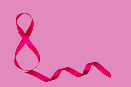 On a pink background, a pink satin ribbon in the form of an eight. Gift wrap. The concept of March 8 and Valentine's Day.A greeting card.の写真素材