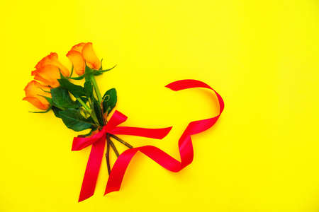 Three yellow roses in a bouquet on a yellow background. A gift bouquet of roses. A greeting card. Empty space for the text.の写真素材