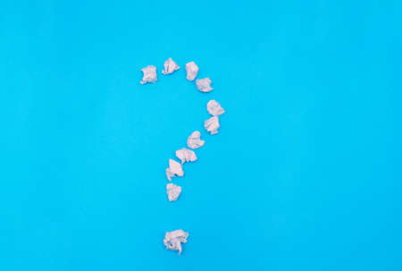 A question mark on a blue background. The question mark is made of crumpled paper. Reflection on the...