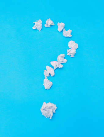A question mark on a blue background. The question mark is made of crumpled paper. Reflection on the...