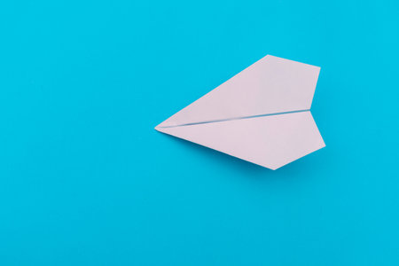 A plane made of paper on a blue background.The plane is made by hand. Origami paper.の写真素材
