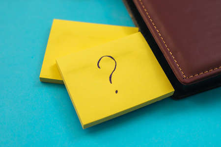 Stickers in the shape of a yellow square are placed on a blue background. Notepads for notes and reminders. A question mark is written on the leaf.の写真素材