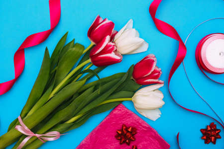 Packaging of a bouquet of pink and white tulips. On a blue background are flowers, wrapping paper,...