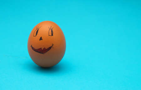 Chicken eggs with painted faces on a blue background. The concept of the Easter holiday. Egg decoration.Empty space for the text.の写真素材