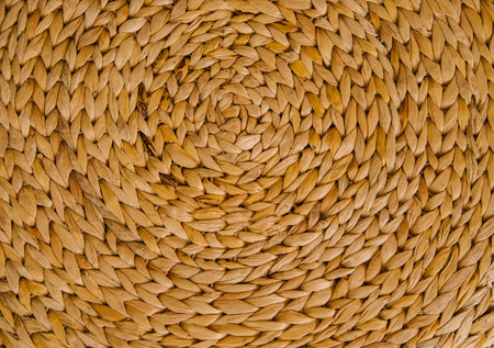 Wicker basket or interior decor close-up. The texture of weaving in a circle. The material is bamboo or reed. Handmade work. The background is made of beige rods.の写真素材