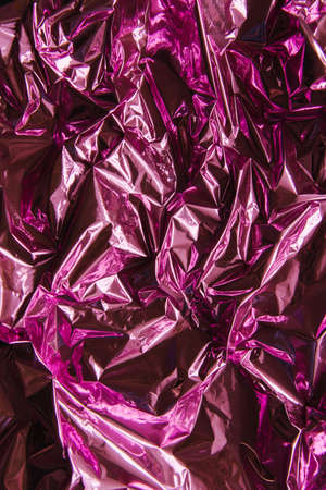 Crumpled pink foil. The background shimmers with rainbow colors. Bright festive background and texture.の写真素材