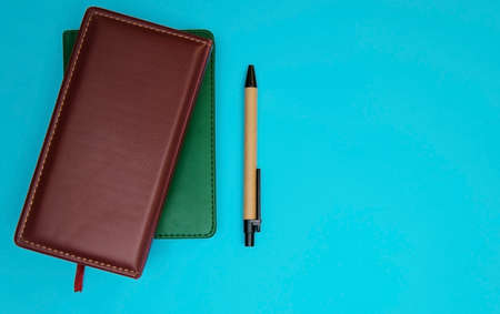 Notepad and pen on a blue background. Soft leather cover and paper pen. The topic of business and education.の写真素材