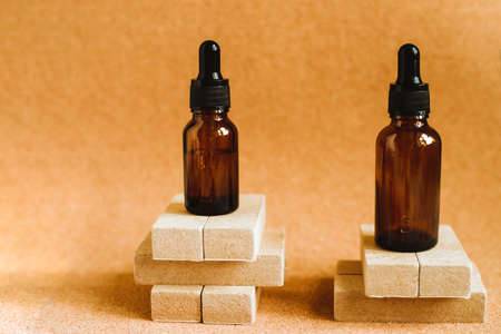 Cosmetic oil in a container with an eyedropper is on the podium. Essential oil for aromatherapy. The...