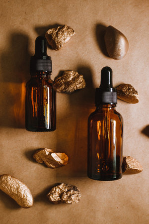 Cosmetic oil in a container with an eyedropper lies among the stones. Essential oil for aromatherapy. Beige is the natural color of the composition and the stones are golden in color.の写真素材