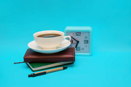 A cup of coffee, a watch, and a notebook on a blue background. The concept of the business theme. Packing in the early morning. Planning of work and recreation.の写真素材