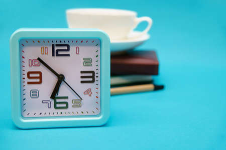A cup of coffee, a watch, and a notebook on a blue background. The concept of the business theme....