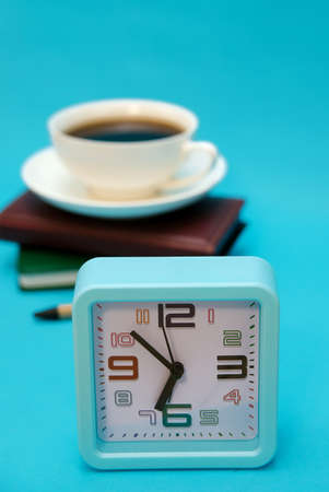 A cup of coffee, a watch, and a notebook on a blue background. The concept of the business theme. Packing in the early morning. Planning of work and recreation.の写真素材