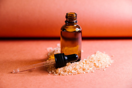 One bottle of dark glass cosmetic oil stands against a background of sea salt. Face and body skin care. Beauty treatments in the salon and at home. Alternative medicine.の写真素材
