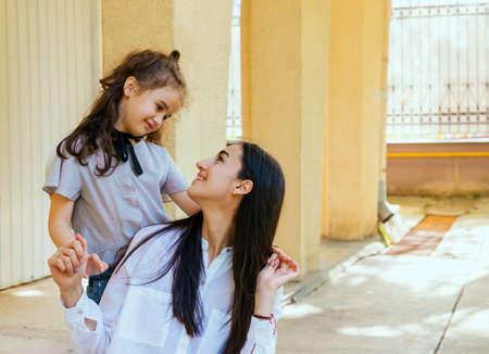A beautiful young woman and a little daughter are sitting and looking at each other. Family leisure and recreation. Maternal care and love. Mother's Day and March 8.の写真素材