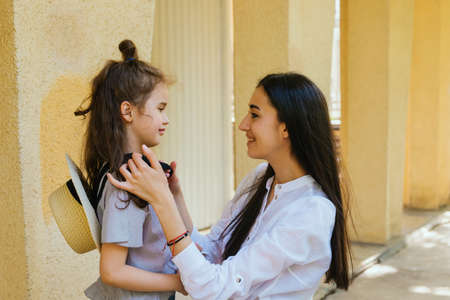 A beautiful young woman adjusts her little daughter's hair. Family leisure and recreation. Maternal care and love. Mother's Day and March 8.の写真素材