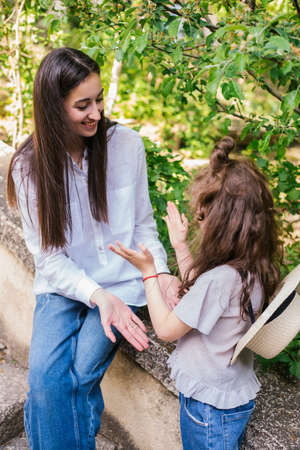 A young mother holds her little daughter's hand and talks. The concept of a strong family, maternal love and tenderness.の写真素材