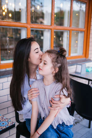 A young mother embraces her little daughter. The girl is sitting in the arms of a woman. The concept...