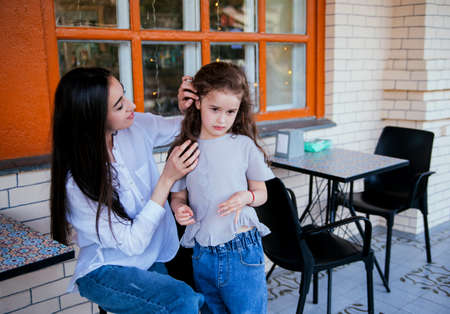 A beautiful young woman fixes her little daughter's hair. Family leisure and recreation. Motherly care and love. Mother's Day and March 8.の写真素材