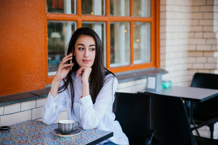 A young pretty girl is talking on a mobile phone with friends or relatives. A happy woman uses her smartphone to make video calls to friends and parents.の写真素材
