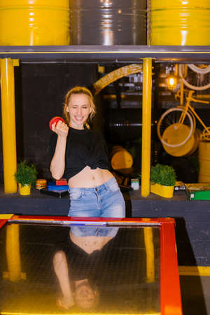 A young woman plays table air hockey. The girl laughs and smiles. Fun and active leisure. Games for...