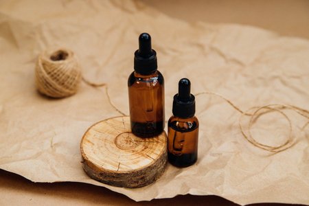 Cosmetic oil in a container with an eyedropper stands on a podium made of sawn wood. Essential oil for aromatherapy.Monochrome image.の写真素材