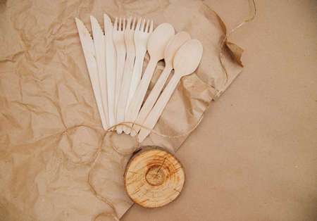 Eco-friendly disposable kitchen utensils on crumpled kraft paper. Wooden forks, spoons and knives. Recycling of dishes and reuse.Taking care of the environment.の写真素材