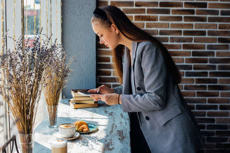 People, leisure and technology concept: young woman photographing sweet dessert on mobile phone, girl taking photo of her breakfast using cell phone camera.の写真素材