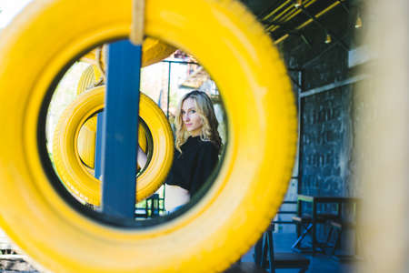 Portrait of a young woman. The girl is standing among the yellow car tires.Creative room decor. A beautiful woman with long hair.の写真素材