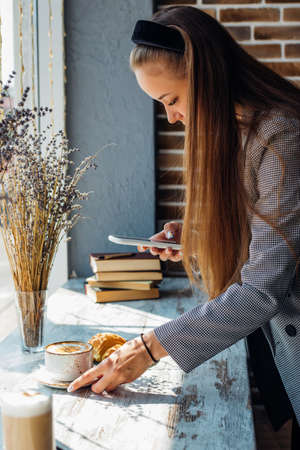 People, leisure and technology concept: young woman photographing sweet dessert on mobile phone, girl taking photo of her breakfast using cell phone camera.の写真素材