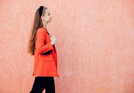 A happy young woman with a bag in her hands is walking down the street. A cheerful girl in a stylish suit, a confident business lady, ready for an office meeting.の写真素材