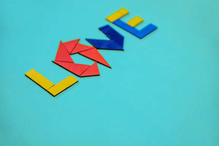 The inscription love on a blue background. Colored letters made of wooden geometric shapes. Creativity and imagination. The concept of Valentine's Day and wedding.の写真素材