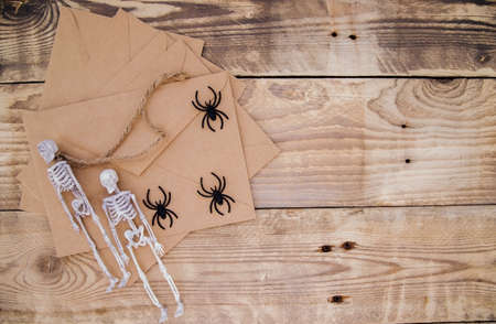 A kraft paper envelope and felt skeletons, spiders, around on a wooden background. Halloween decor. Handmade holiday decorations.の写真素材