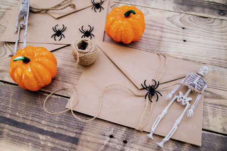 A kraft paper envelope and felt bats, skeletons, spiders, pumpkins around on a wooden background. Halloween decor. Handmade holiday decorations.の写真素材
