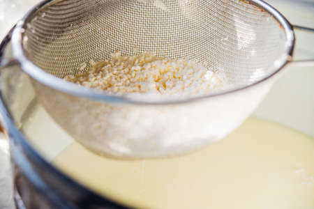 Cooking homemade cottage cheese handmade. Cottage cheese is squeezed through a metal sieve....