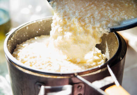 Cooking homemade cottage cheese handmade. Cottage cheese is squeezed through a metal sieve....
