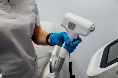 Preparation of the workplace before the laser hair removal procedure. Skin care, cosmetic procedures.An office in a beauty salon.Women's hands in blue gloves.の写真素材