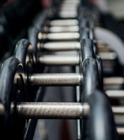 A rack with heavy metal dumbbells in the gym or fitness club. Exercise and a healthy lifestyle. Strength exercises.の写真素材