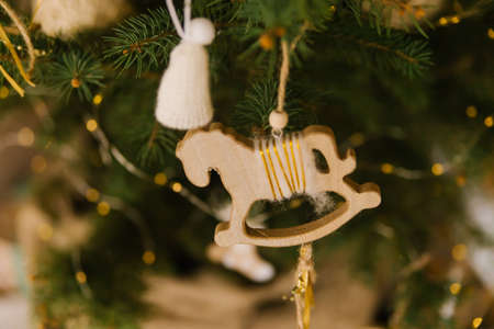 A wooden toy horse is hanging on a green branch of a fir tree. Holiday decorations. Handmade toys. Christmas and New Year.の写真素材