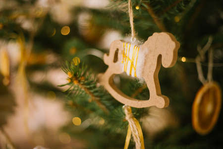 A wooden toy horse is hanging on a green branch of a fir tree. Holiday decorations. Handmade toys. Christmas and New Year.の写真素材