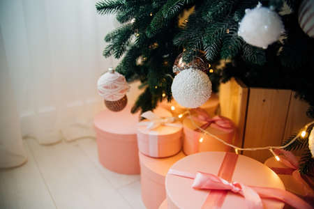 Gift boxes are under the Christmas tree. Pink boxes tied with satin ribbon.Festive mood. A surprise for family and friends.の写真素材
