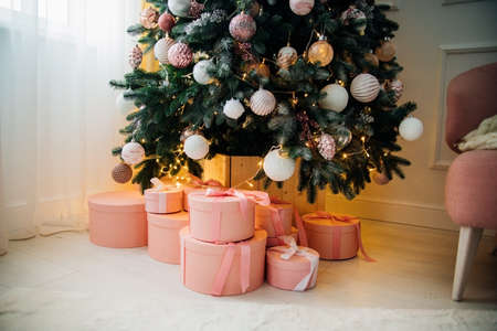 Gift boxes are under the Christmas tree. Pink boxes tied with satin ribbon.Festive mood. A surprise for family and friends.の写真素材