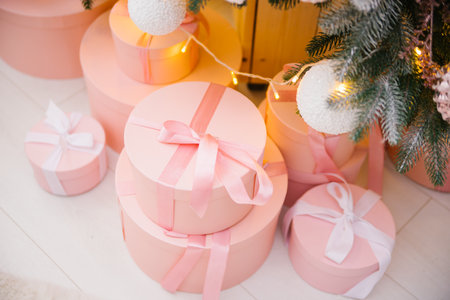 Gift boxes are under the Christmas tree. Pink boxes tied with satin ribbon.Festive mood. A surprise...