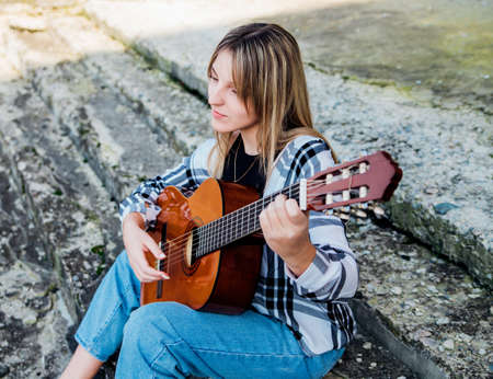 The girl plays the guitar. A hobby for a teenager. learning music. Composer and author. Modern youth style.の写真素材