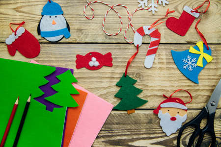 Making handmade Christmas toys from felt with your own hands. Decorations for the Christmas tree or home interior. Step 3. Finished toys on a wooden background.の写真素材