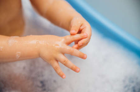 Baby pens in a blue bubble bath. Baby detergent, hygiene. Baby skin care. Background and texture of soap bubbles.の写真素材