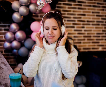 A young pregnant woman is sitting resting in a cafe and listening to music. The girl in the headphones is thinking. Waiting for the birth of a child.の写真素材