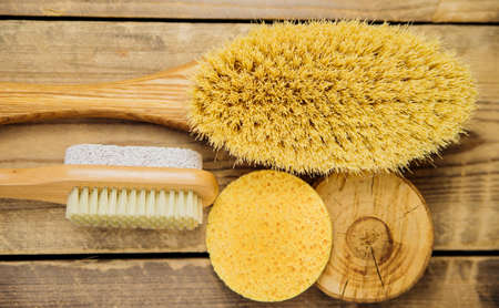 Wooden brush for dry body massage, porous sponge for the face. Anti-cellulite brush for body and leg massage on a wooden background. Eco-friendly material.の写真素材