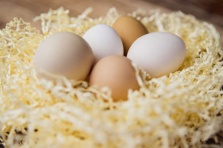 Easter eggs of natural color in a nest on a wooden background. Chicken eggs in straw. Preparation...