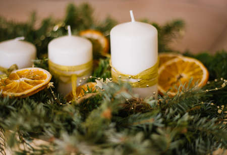 Festive decoration of Christmas and New Year's table with rustic handmade details in natural colors. Fragrant fir branches, orange slices and candles. The atmosphere of celebration and comfort.の写真素材