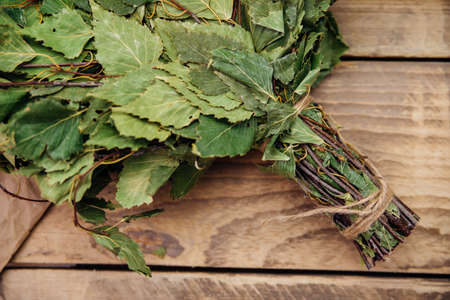 A dry birch broom lies on a wooden background. Accessories for baths and saunas. spa treatments. Natural, eco-friendly materials.の写真素材